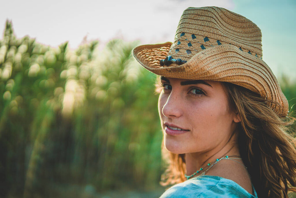 A shallow focus shot of a European female with a cowboy hat on the beach - Fotó, kép