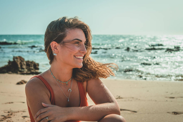 Kaunis eurooppalainen nainen, jolla on oranssi uimapuku hiekkarannalla - Valokuva, kuva