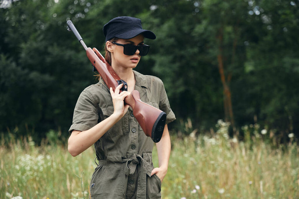 Vojenská žena Žena se zbraněmi v tmavých brýlích zelená kombinéza čerstvý vzduch  - Fotografie, Obrázek