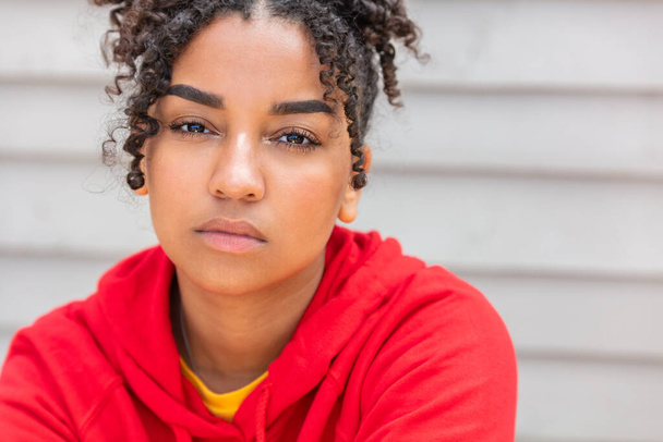 Menina adolescente adolescente jovem afro-americana mista mulher biracial fora olhando pensativo e vestindo capuz vermelho
 - Foto, Imagem