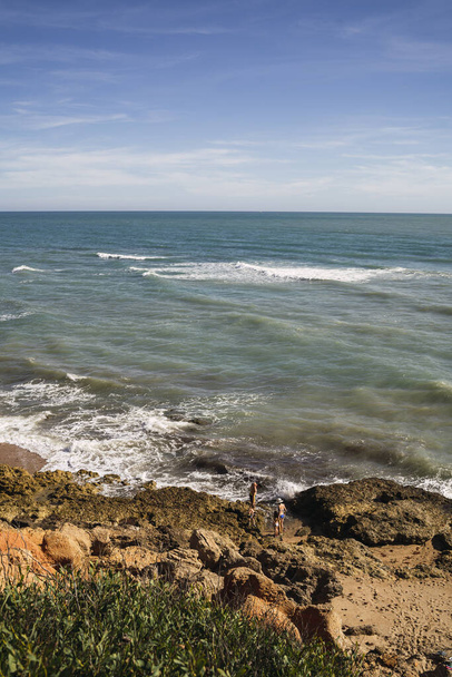 A vertical shot of the Chiclana beach surrounded by the sea under a blue sky in Cadiz, Spain - Foto, imagen