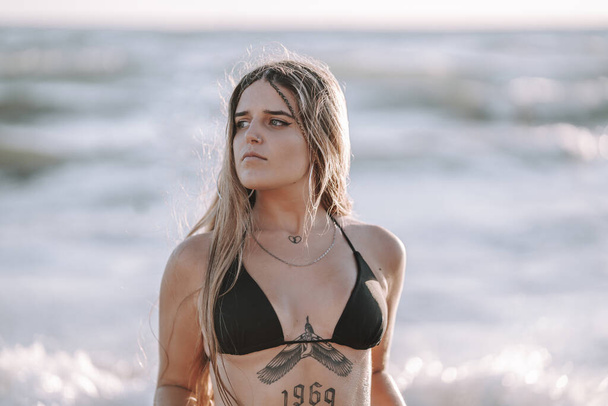 An attractive female with tattoos relaxing at the seaside in La Caleta beach in Cadiz, Spain - 写真・画像