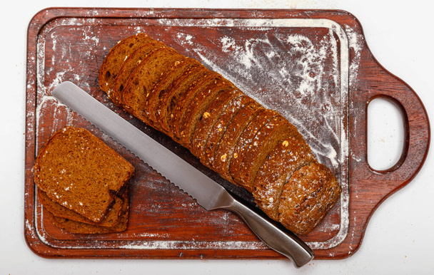 Koyu ahşap zemin üzerinde dilimlenmiş taze kepekli veya çoklu tahıllı ekmeğin üst görüntüsü.. - Fotoğraf, Görsel