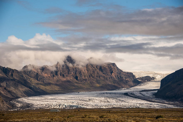 A beautiful scenery of the glaciers of Iceland under beautiful white fluffy clouds - Фото, зображення