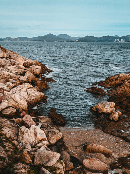 A vertical shot of a rocky beach and wavy sea - Foto, Imagen