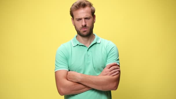 confused casual guy crossing arms, thinking and having no idea, standing on yellow background - Footage, Video