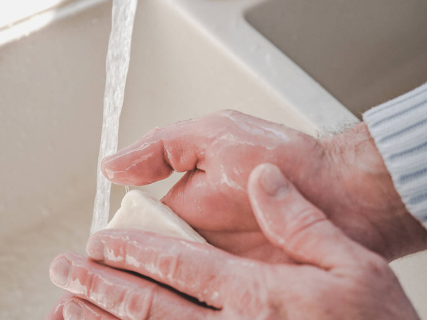 Men's hands and a bar of soap on a background of a vintage tap. Top view, closeup. Health Care and Prevention Concept - Photo, Image