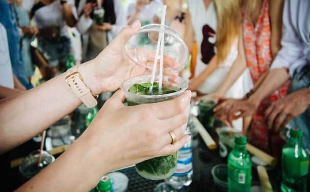 woman closes the lid on a plastic cup with mojito - Photo, Image