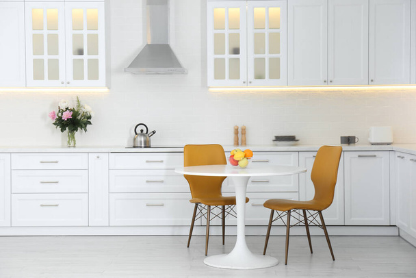 Table with orange chairs in modern kitchen interior - Foto, imagen