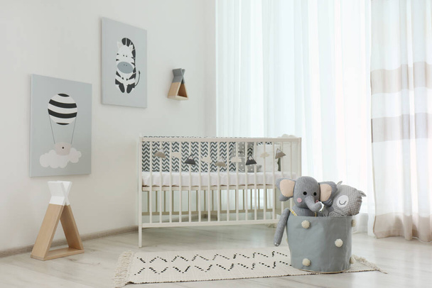 Stylish baby room interior with crib and cute pictures on wall - Foto, afbeelding