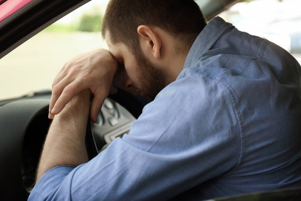 Tired man sleeping on steering wheel in his car - Foto, Imagen
