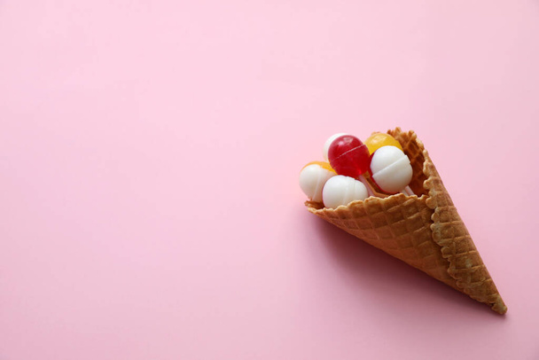 Delicious lollipop candies in wafer cone on pink background, top view. Space for text - Φωτογραφία, εικόνα
