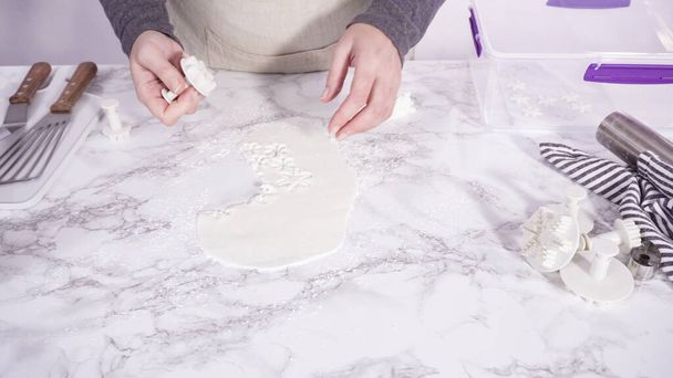 Step by step. Cutting out snowflakes with cookie cutters out of white fondant on a marble counter. - Photo, Image
