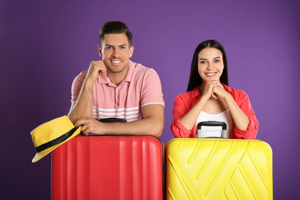 Happy couple with suitcases for summer trip on purple background. Vacation travel - Foto, imagen