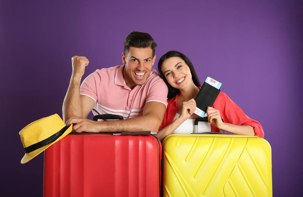 Gelukkig stel met koffers voor een zomervakantie op paarse achtergrond. Vakantie reizen - Foto, afbeelding