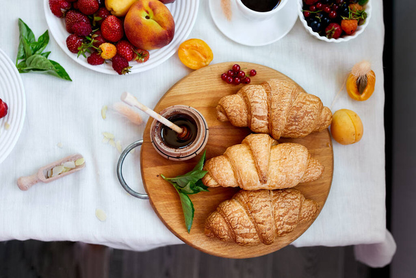Mesa de café da manhã continental servida com croissant francês tradicional, frutas e café, espaço de cópia de vista superior, quadro
. - Foto, Imagem