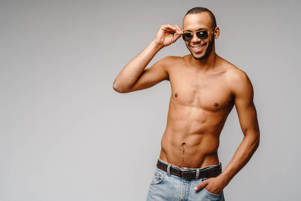 Sexy young muscular african american man shirtless wearing sunglasses over light grey background - Foto, immagini