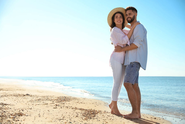 Happy young couple on beach near sea. Honeymoon trip - Фото, изображение