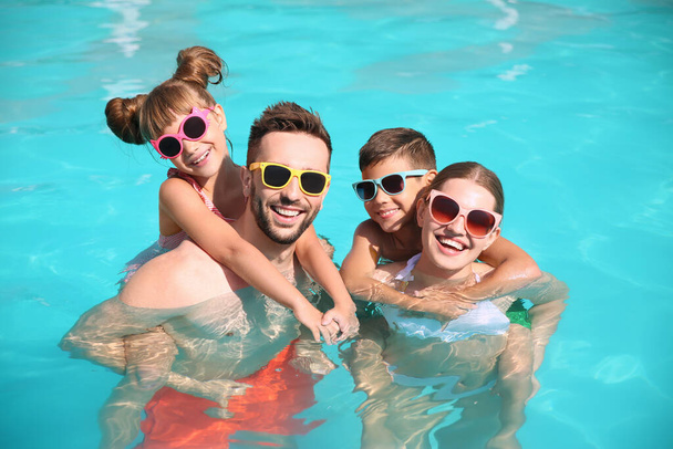 Happy family in swimming pool on sunny day - Фото, зображення