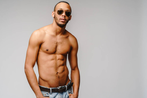 Sexy young muscular african american man shirtless wearing sunglasses over light grey background - Foto, Imagem