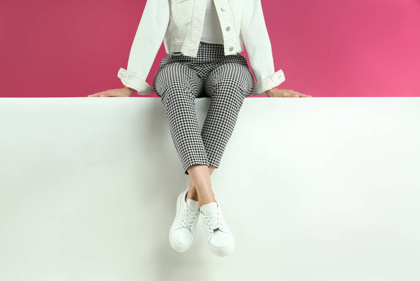 Woman in stylish shoes sitting on color background, closeup - Фото, зображення