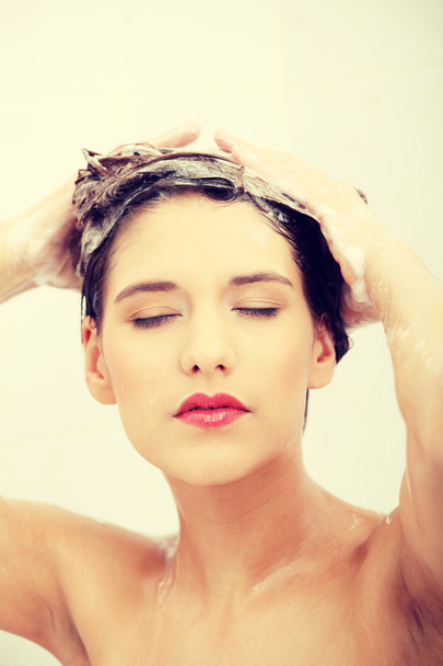 Beautiful young woman washing her hairs - 写真・画像