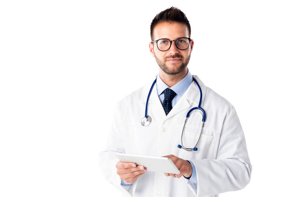 Studio shot of male doctor holding digital tablet in his hand while standing at isolated white background. Copy space. - Φωτογραφία, εικόνα