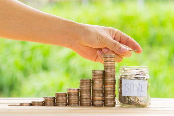 White hand man holding coin to putting in Jar or glass bottle for saving with nature green background. Saving money, Saving concept - Photo, image