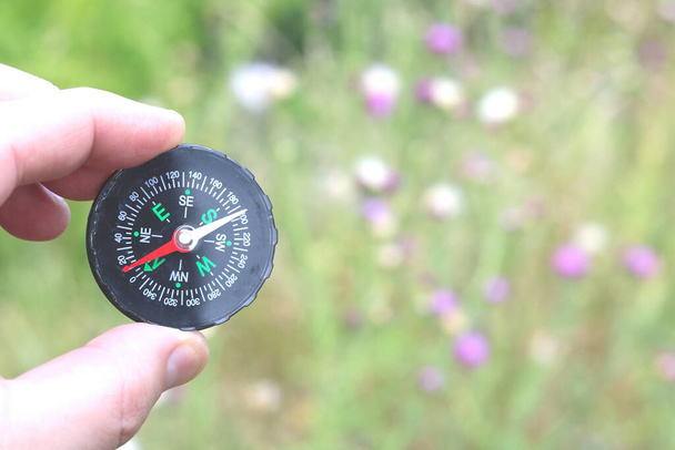 Starý klasický navigační kompas v ruce na přírodním pozadí jako symbol cestovního ruchu s kompasem, cestování s kompasem a outdoorových aktivit s kompasem - Fotografie, Obrázek