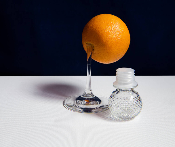 still life with an orange orange and a broken leg from a glass on a dark background - Photo, Image