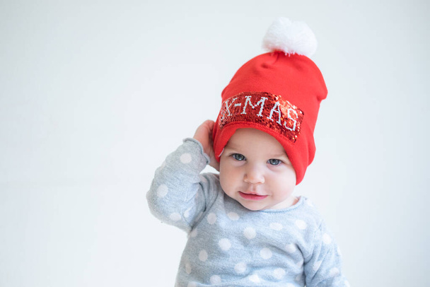 Infant baby portrait on white monochrome background in red hat with letters merry christmas. Little santa. Happy holidays - Fotoğraf, Görsel