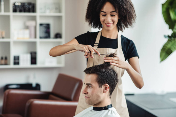 Молодой человек стрижется в парикмахерской - Фото, изображение