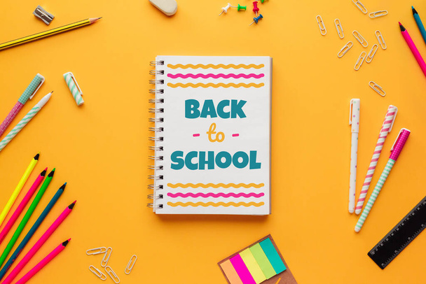 Stockfoto van terug naar school concept met een notitieboekje met belettering en wat briefpapier voorwerpen op een gele achtergrond - Foto, afbeelding