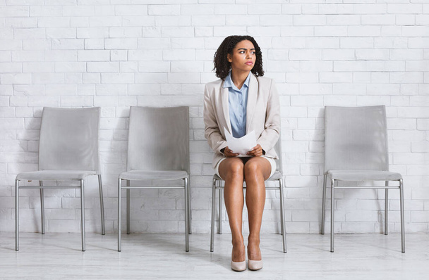Ανήσυχη μαύρη γυναίκα με βιογραφικό σημείωμα περιμένει για συνέντευξη εργασίας στο χώρο της εταιρείας, κενό χώρο - Φωτογραφία, εικόνα