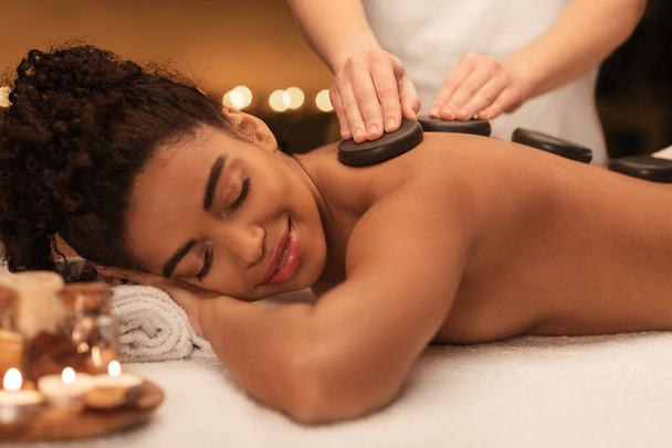 Senhora africana recebendo massagem profissional de pedra quente no spa
 - Foto, Imagem