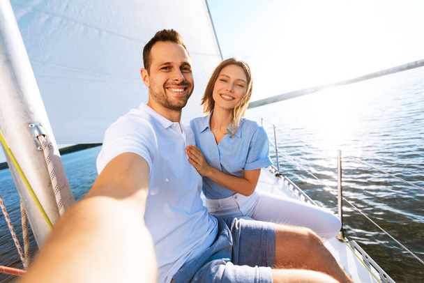 para co Selfie siedzi na pokładzie ciesząc się żeglarstwo na wybrzeżu - Zdjęcie, obraz