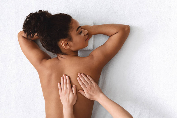 Black lady enjoying relaxing body massage at spa - Foto, Imagem