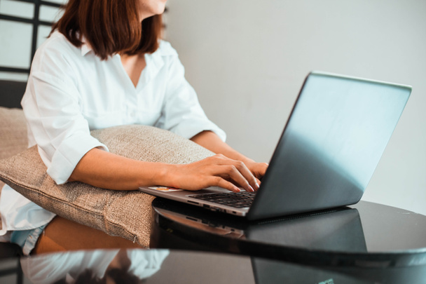Nuori nainen työskentelee kannettavan tietokoneen kun istuu olohuoneessa. työ kotoa käsite - Valokuva, kuva