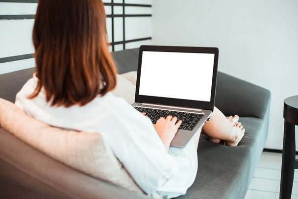 молода жінка працює на ноутбуці, сидячи у вітальні. робота з домашньої концепції
 - Фото, зображення