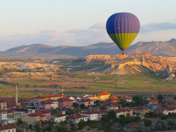 Goreme, Turquia, 15 de maio de 2015. Um balão voa sobre a aldeia de Goreme e seus arredores ao nascer do sol
. - Foto, Imagem
