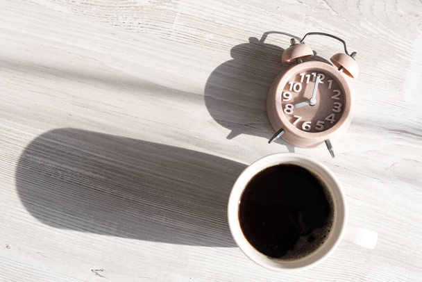 Крупный план будильника и чашки кофе имеет доброе утро и утреннее солнце. Весёлое начало дня, место для копирования - Фото, изображение