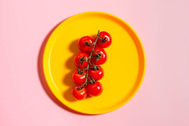 Třešňové rajče na žlutém talíři na růžové. Koncept. Zelenina. Stín. - Fotografie, Obrázek