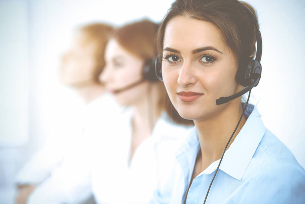 Call center. Focus on beautiful business woman in headset - Foto, Bild