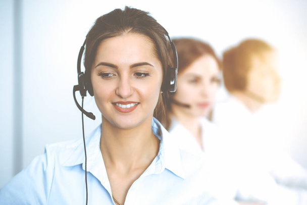 Call center. Focus on beautiful business woman in headset - Zdjęcie, obraz
