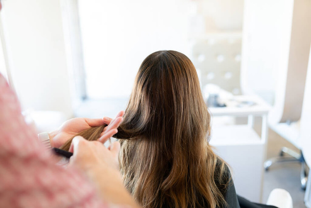 Male hairdresser combing hair of female customer at beauty salon - Photo, image