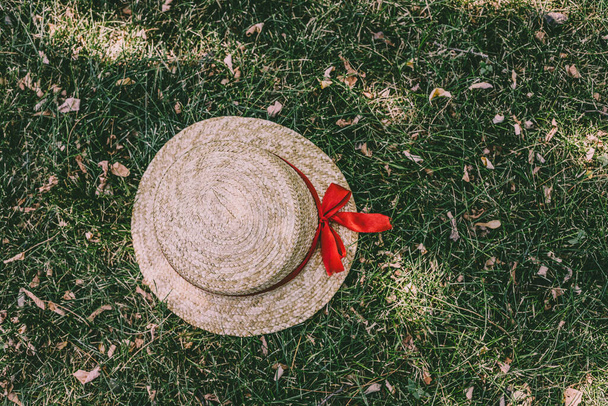 Vista dall'alto di bellissimo cappello estivo in paglia con nastro rosso su erba verde. Godersi l'estate - Foto, immagini