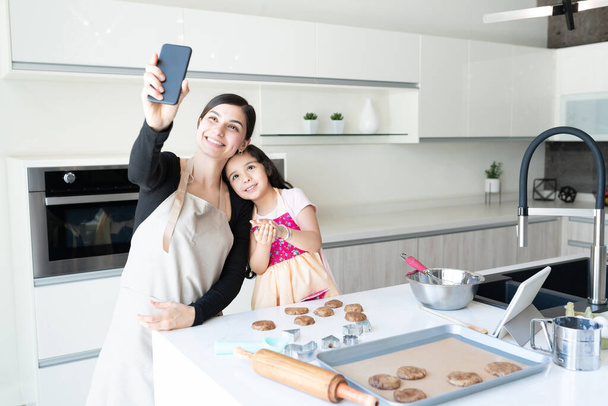 Sourire famille latine prendre selfie tout en préparant des cookies à la maison - Photo, image