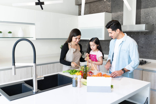 Hispanic cute girl learning to prepare food with family in kitchen - Foto, immagini