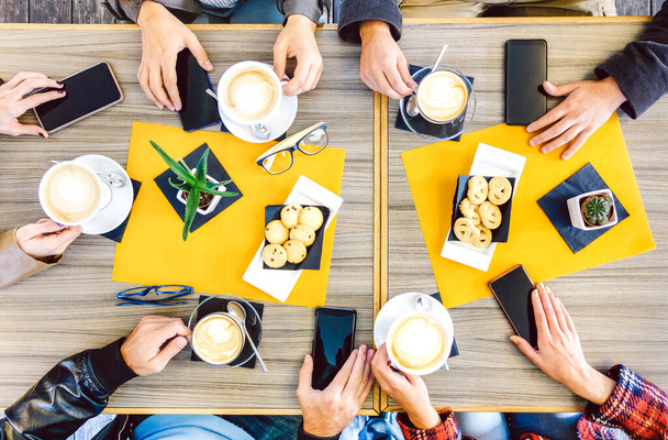 Vista superior de las manos bebiendo en el restaurante cafetería - La gente desayunando junto con los teléfonos inteligentes móviles en el bar de la cafetería de moda - Concepto de estilo de vida en el filtro caliente - Enfoque en la parte central del marco - Foto, imagen