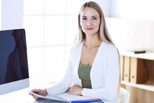 Business woman headshot while working with computer at the desk in modern office. Designer or female lawyer looks beautiful in white casual clothes. Business people concept - Foto, Imagen